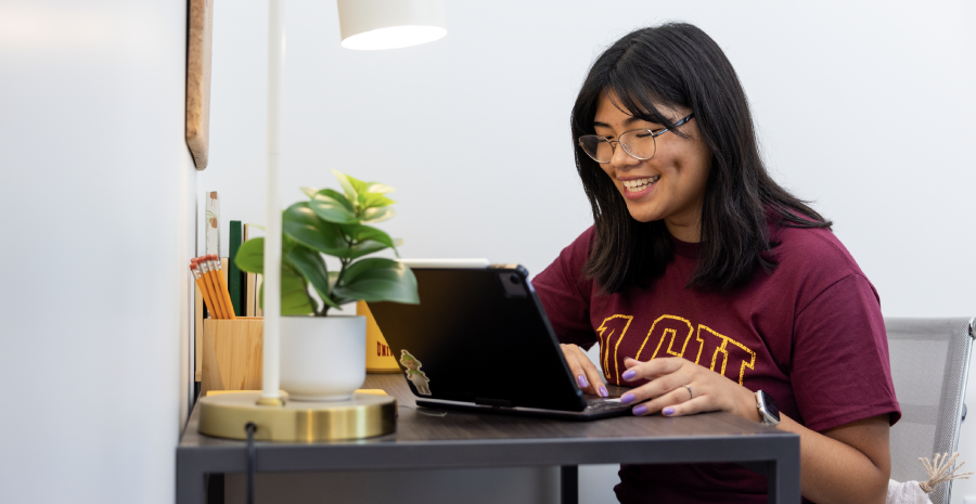 Student smiling while using a laptop
